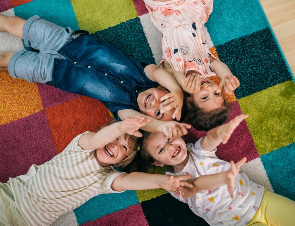 Smiling teacher and little child talking and playing at preschool